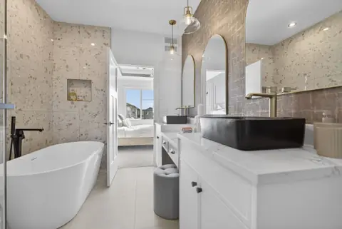 The ensuite: freestanding tub, glass shower and double vanity. Furniture and décor are staging for the photos.