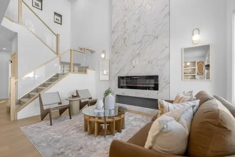 Living room with an electric fireplace and an open-to-above ceiling. Furniture and décor are staging for the photos.