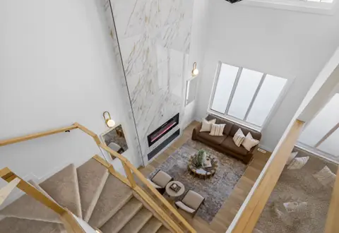 Looking down from the upstairs landing into the open-to-below living room. Furniture and décor are staging for the photos.