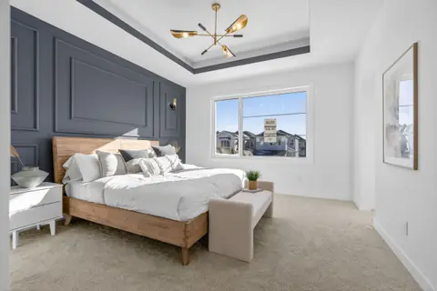 The primary bedroom with a panelled feature wall. Furniture and décor are staging for the photos.