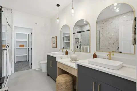 The ensuite with an arched mirror, a freestanding tub and a walk-in shower. Furniture and décor are staging for the photos.