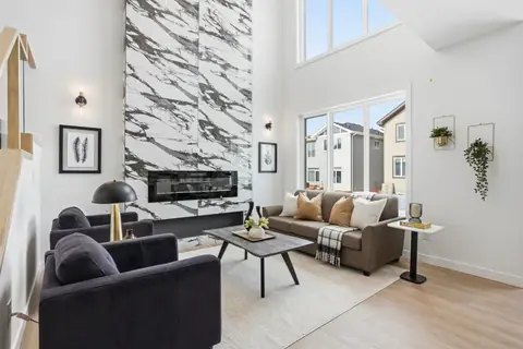 Living room with a full-height feature wall and fireplace — the second Vita home. Furniture and décor are staging for the photos.