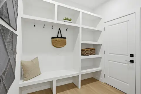 Built-in bench and shelving at the garage entry. Furniture and décor are staging for the photos.